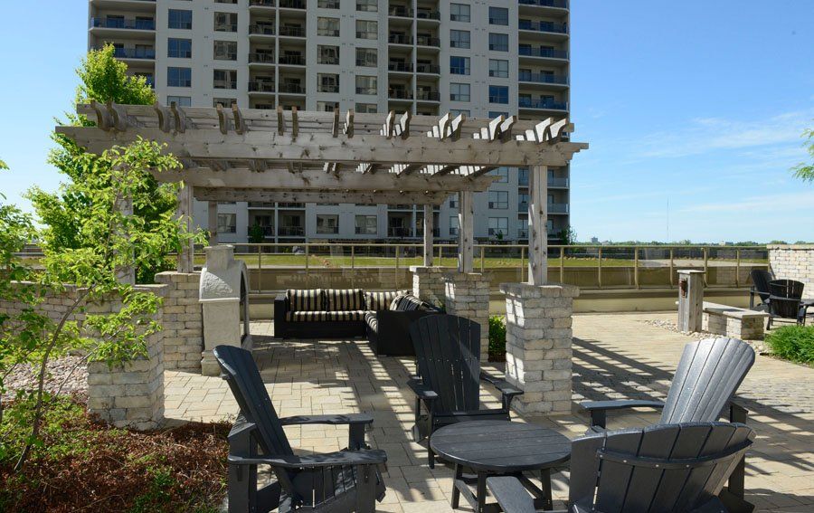 outdoor patio in front of large condo building with wooden gazebo covering lounge area