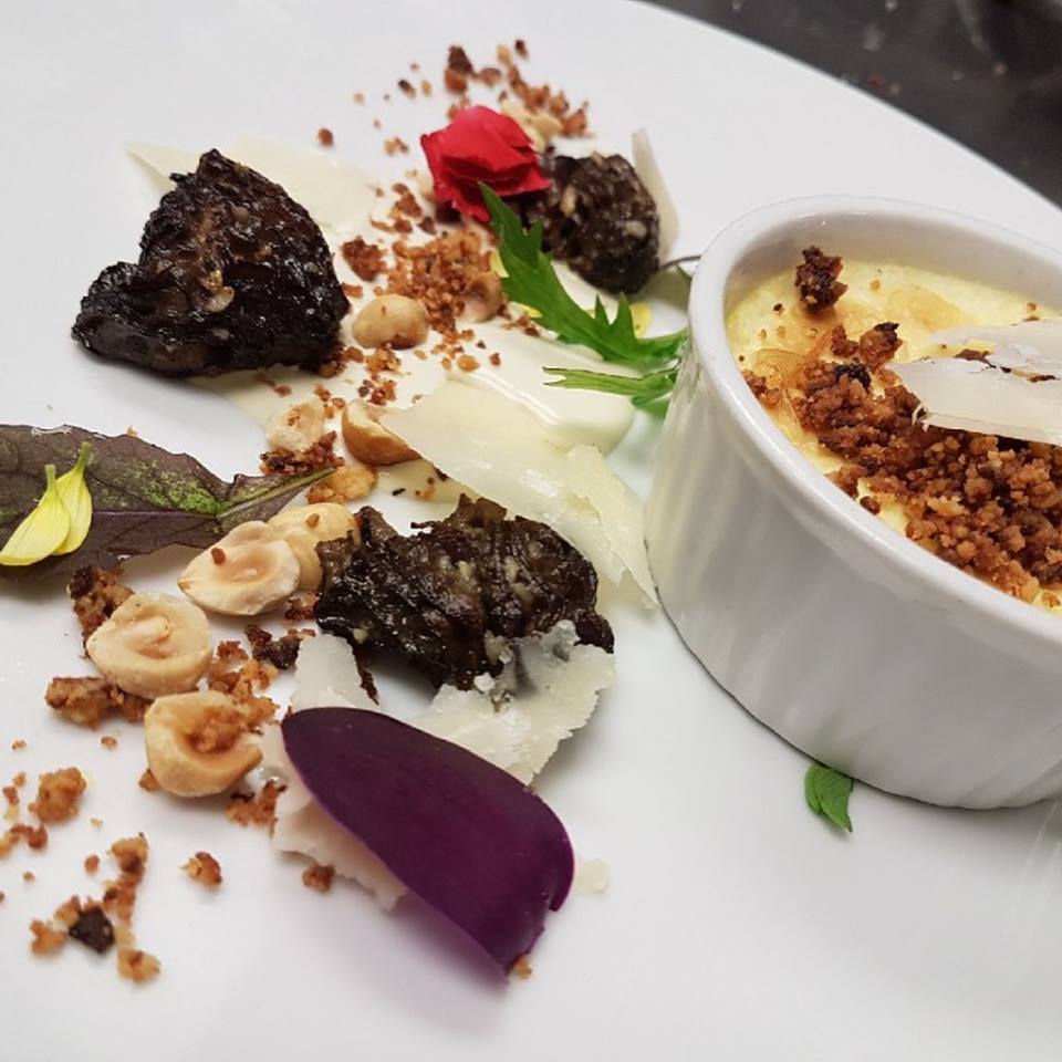 dessert in a ramekin on a plate with nuts and other decorative garnish beside on a white plate