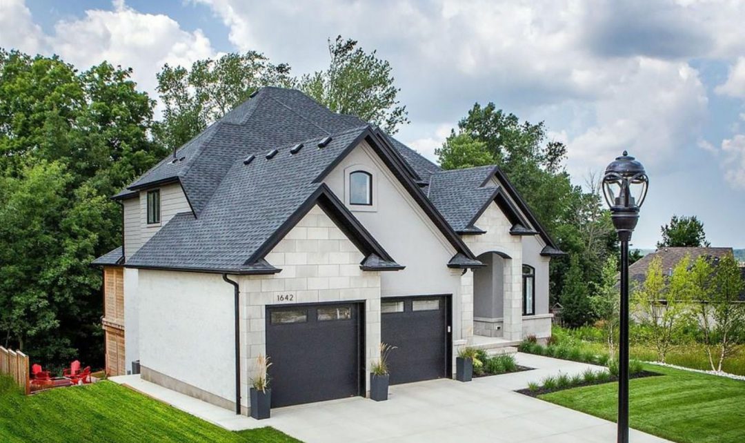 exterior of grey stone home with black finishes and two car garage