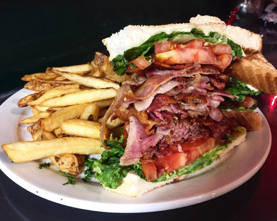 huge BLT sandwich and fries on white circle plate