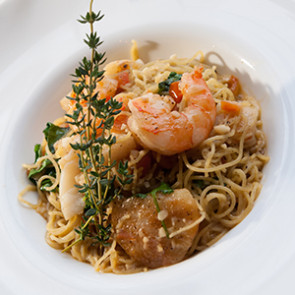 angel hair pasta in bowl with shrimp with herb garnish