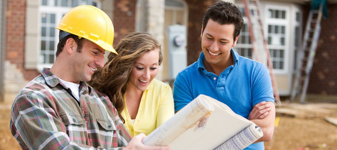 three people looking at blueprints on a construction site and smiling