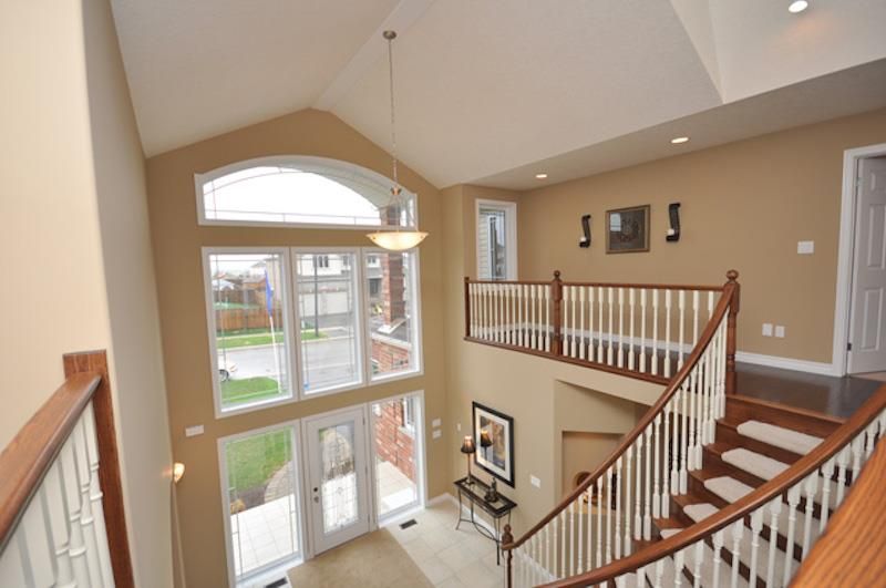 interior foyer of house looking from upstairs to large front window and winding staircase