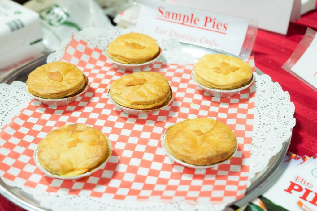 5 sample pies on a red and white checkered cloth with paper labels