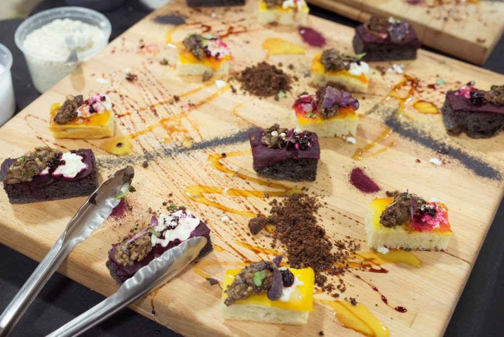 decorated cake samples on a wooden board with tongs