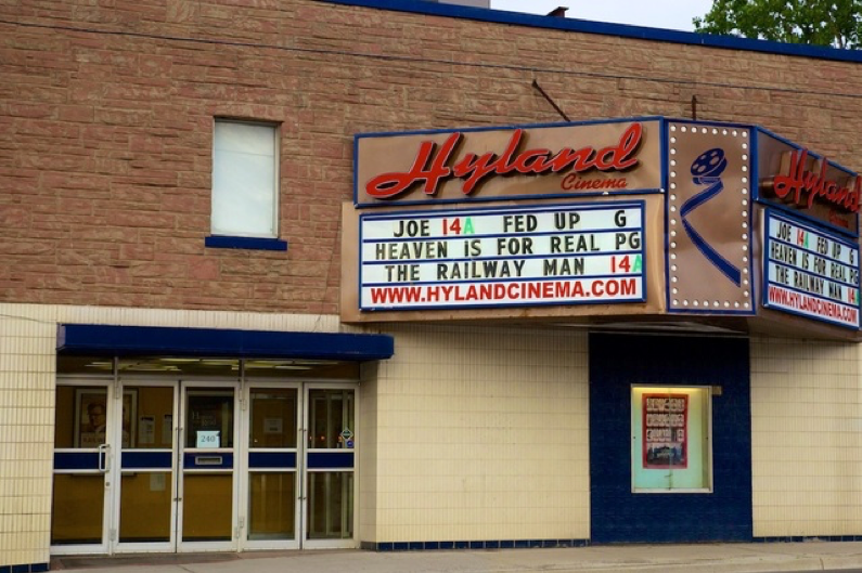 cinema entrance with showcase sign and various movies listed